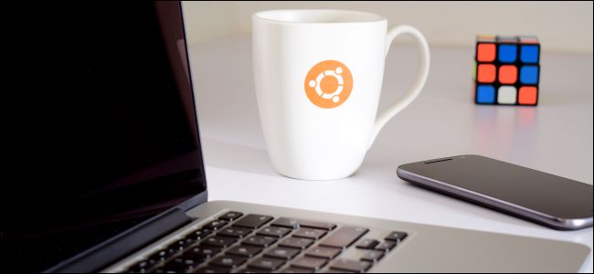 Ubuntu mug next to a laptop, phone, and Rubik's Cube.