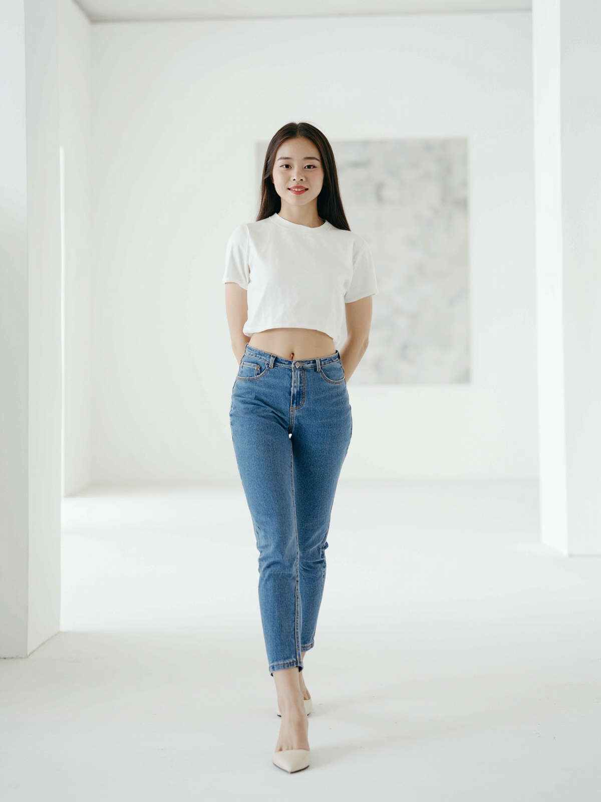 当代美术馆白盒子展厅内穿蓝色低腰紧身牛仔裤的成年女性