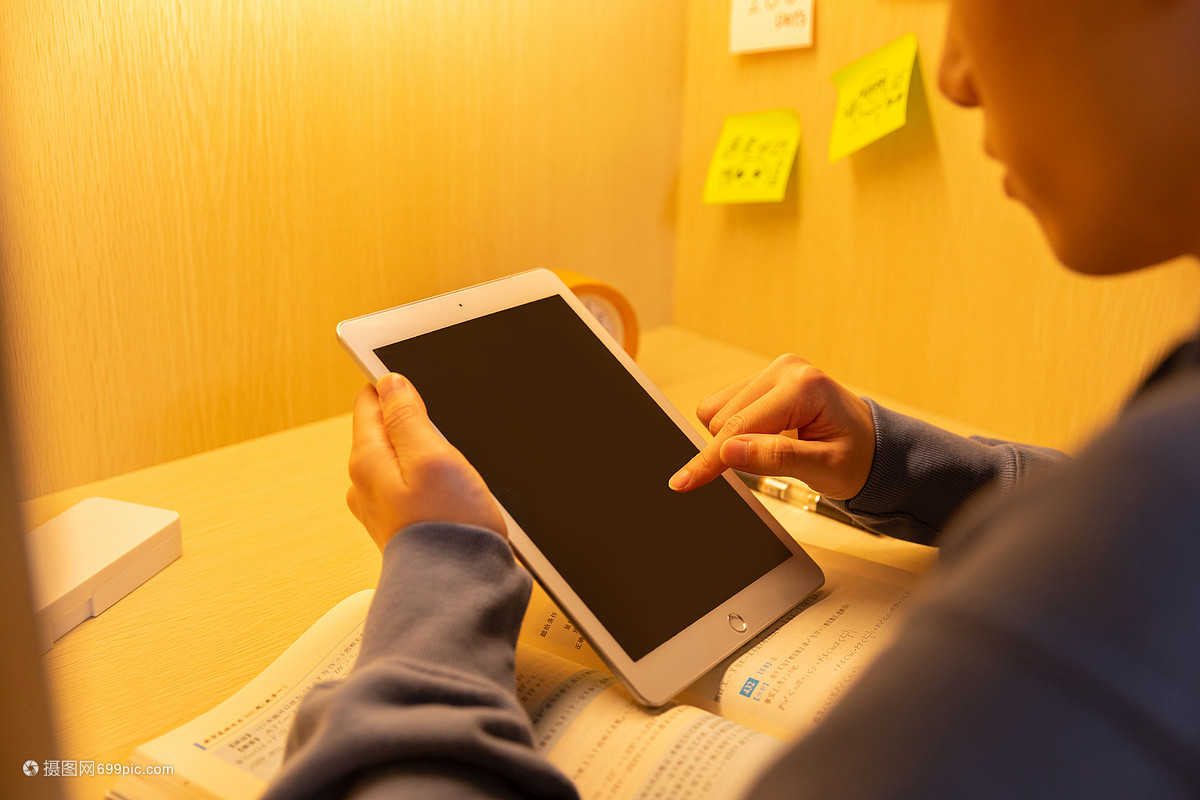 青年男性自习室使用平板电脑特写 夕阳下的错题订正
